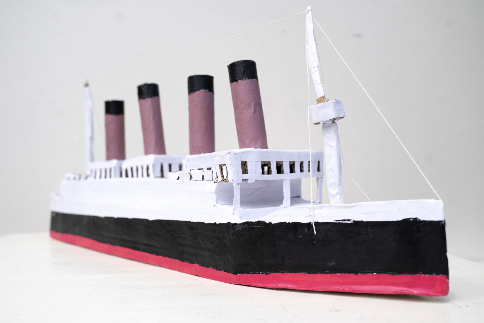 Cardboard miniature of the RMS Titanic. The ship is painted in white, black, red and lilac.